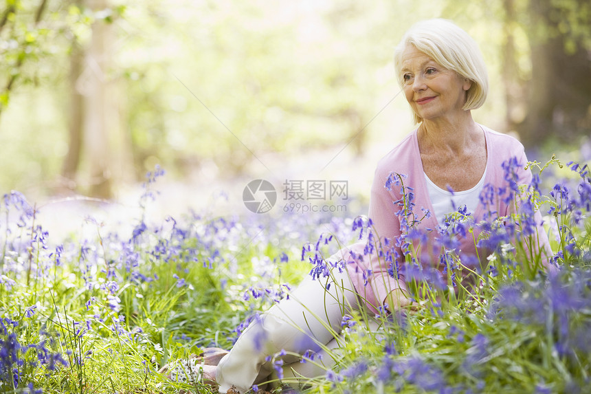 妇女坐在户外 鲜花微笑着女士采摘享受公园女性农村野花木头季节退休图片