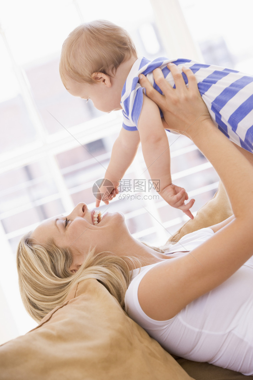 母亲在起居室抱着婴儿微笑女士玩具女儿女孩笑声妈妈女性拥抱家庭家长图片