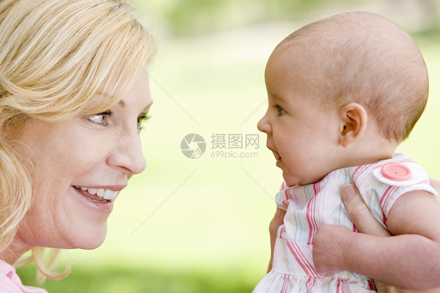 母亲和婴儿在户外微笑妈妈女儿公园拥抱女孩两个人儿童感情家长水平图片