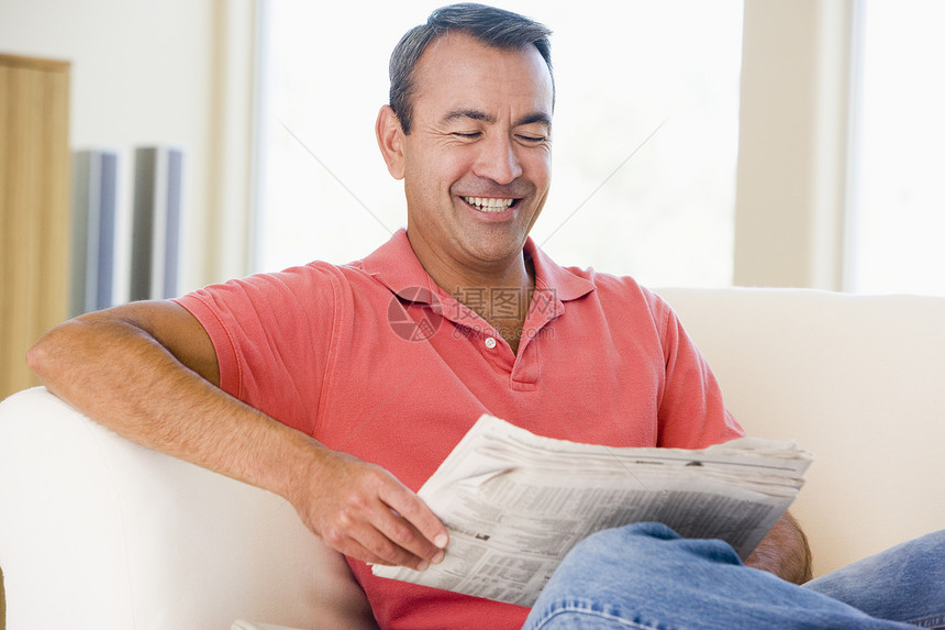 在客厅阅读报纸的人笑着看水平微笑长度成人中年男人长椅时事男性休息室图片