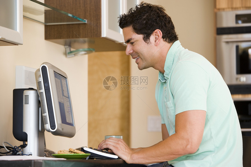 厨房里的男人使用电脑和微笑技术冲浪年轻人工作站水平成人互联网男性桌子图片