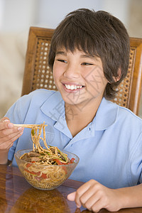 饭厅的年轻男孩在吃中国食物时微笑着笑中餐外卖刀具孩子们美食一个男孩孩子餐具儿童男生儿童食品高清图片素材