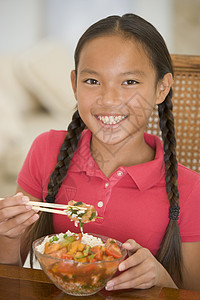 饭厅的年轻女孩在吃中国食物时微笑着笑筷子混血儿用具儿童厨房食品美食孩子们外卖青春期亚洲美食高清图片素材