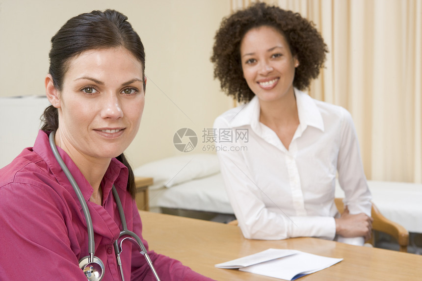 医生办公室里的女人微笑着全科病人医师咨询讨论头肩病历两个人博士中年图片