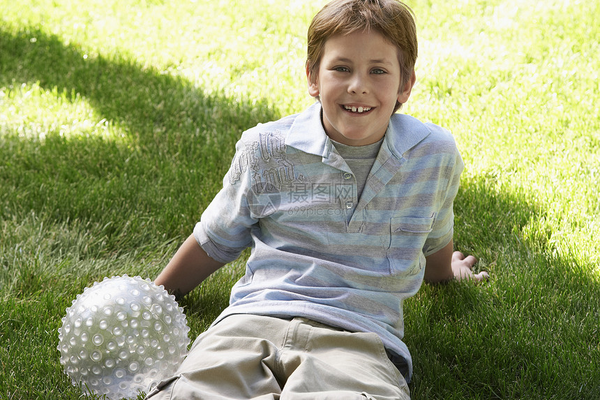 微笑的男孩坐在草地上图片
