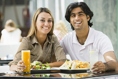 在餐厅吃饭和微笑的情侣薯条水果汁人种情感夫妻食物筹码食品夫妇果汁背景图片