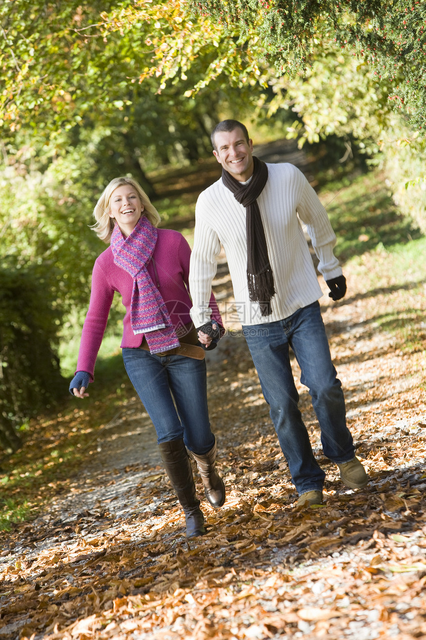 一对夫妇在户外行走 在公园的路上微笑着男朋友人种情绪女朋友情感亲热外表焦距树叶落叶图片