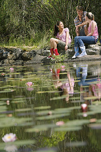荷叶池塘的女孩坐在溪边的年轻朋友青少年冒险时间荷叶黑人远足者男孩们男性睡莲闲暇背景