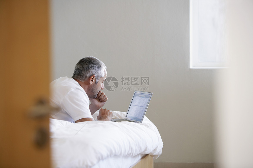 在床铺上使用笔记本电脑的人硬件技术卧室计算机设备障碍沟通用户访问通讯图片