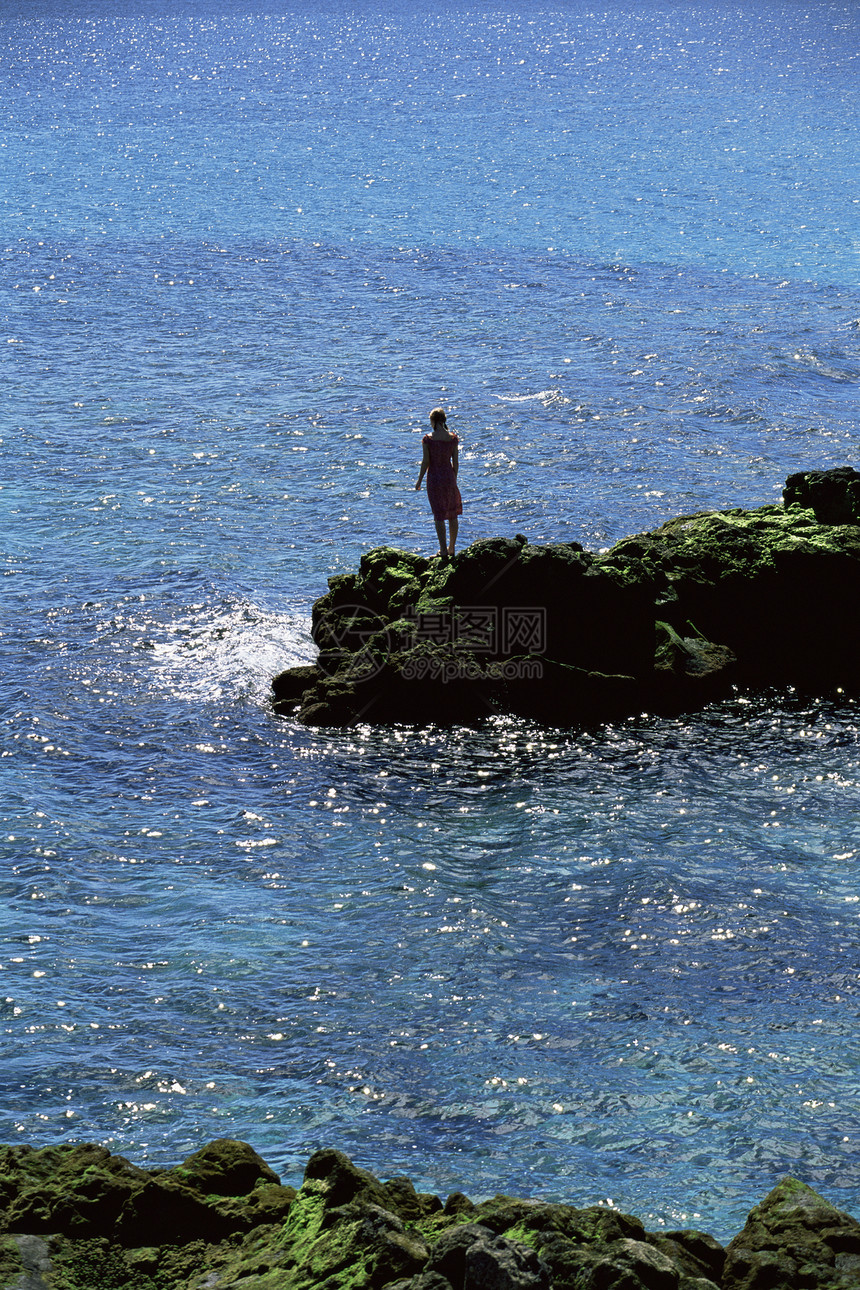 露户妇女站在大岩石上海洋远处女性海岸人种外表成人支撑女士远距离相机海域图片