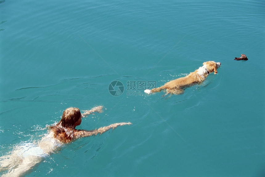 女子和户外狗在湖中游泳图片