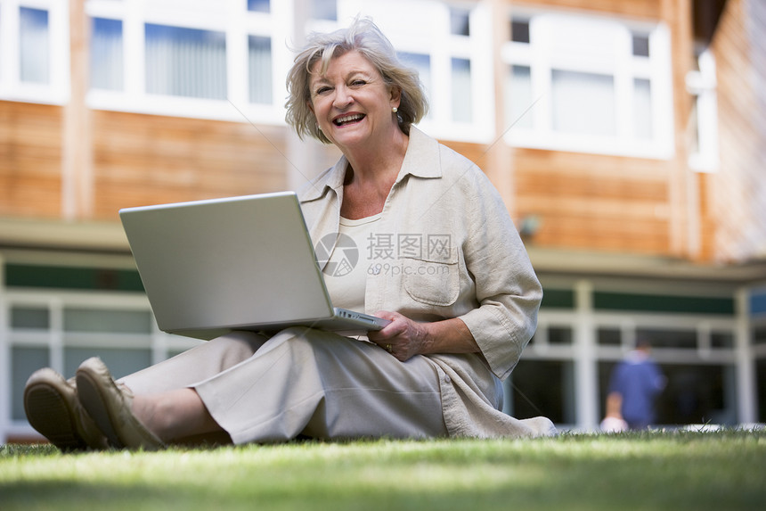 妇女用笔记本电脑躺在学校草坪上休闲眼神情感成年人服饰服装情绪衣服外表老化图片