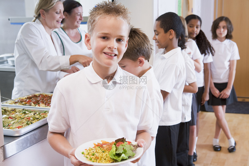 餐厅线上的学生 其中一人拿着健康饮食 看照相机深入田间用餐同学们男生食堂孩子工人谷物亚裔孩子们男孩们图片