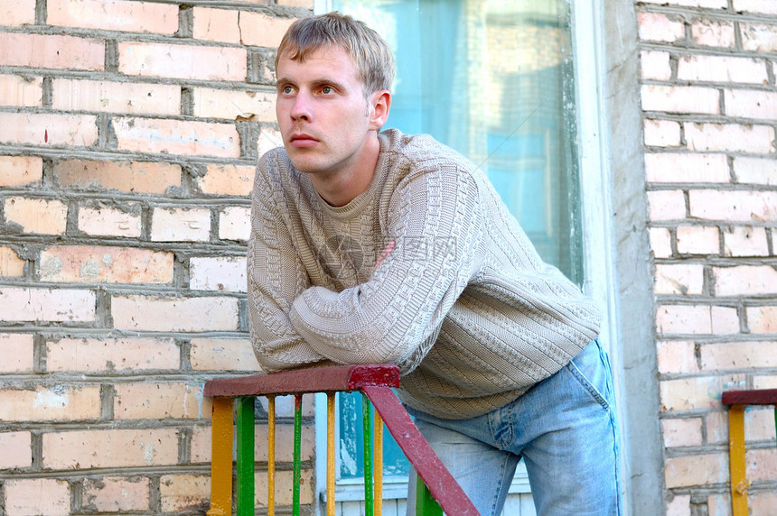 年轻时尚的男人住在砖墙附近的楼梯上小鹿玻璃倾斜衣服橙子头发金发女郎扶手窗户脚步图片