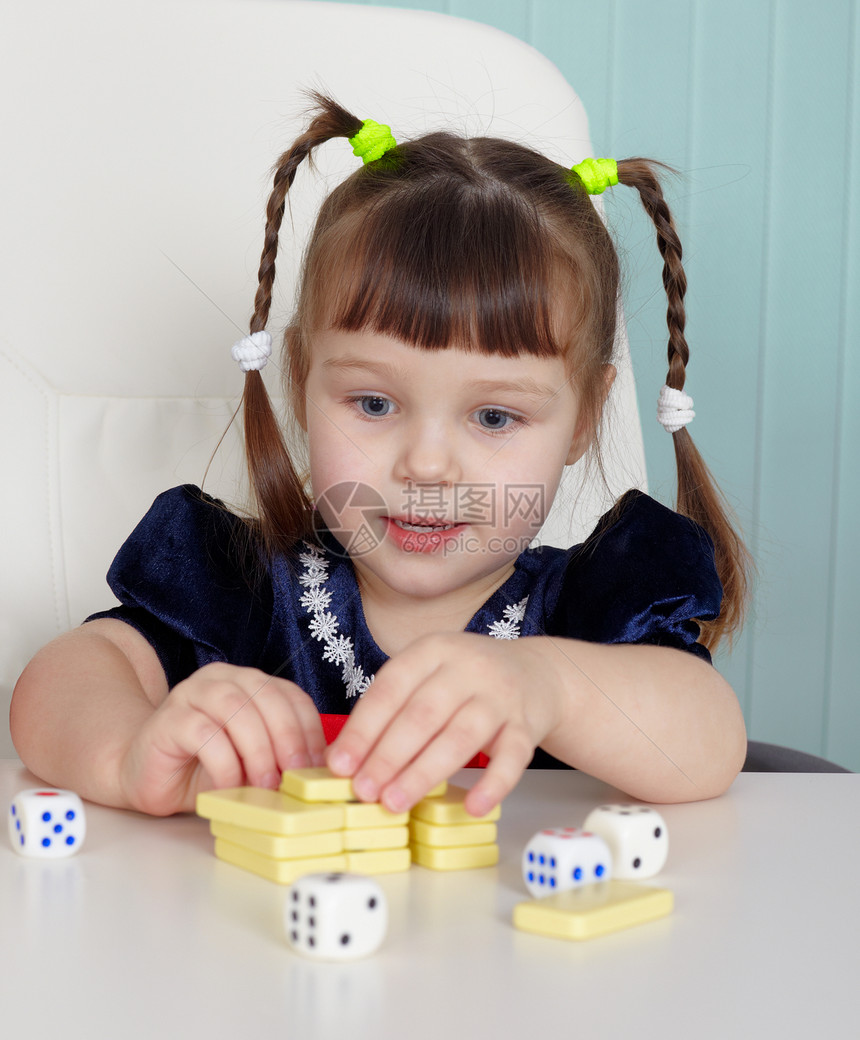 快乐的美丽孩子玩玩具在桌上女孩骰子蓝色笑脸童年桌子骨牌白色柜台婴儿图片