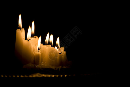一群在黑暗中燃烧的白色蜡烛团体灯芯背景图片