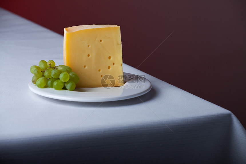 一块奶酪和一堆葡萄玫瑰工匠酒杯熟食奶制品桌布粉色饮料食物紫色图片