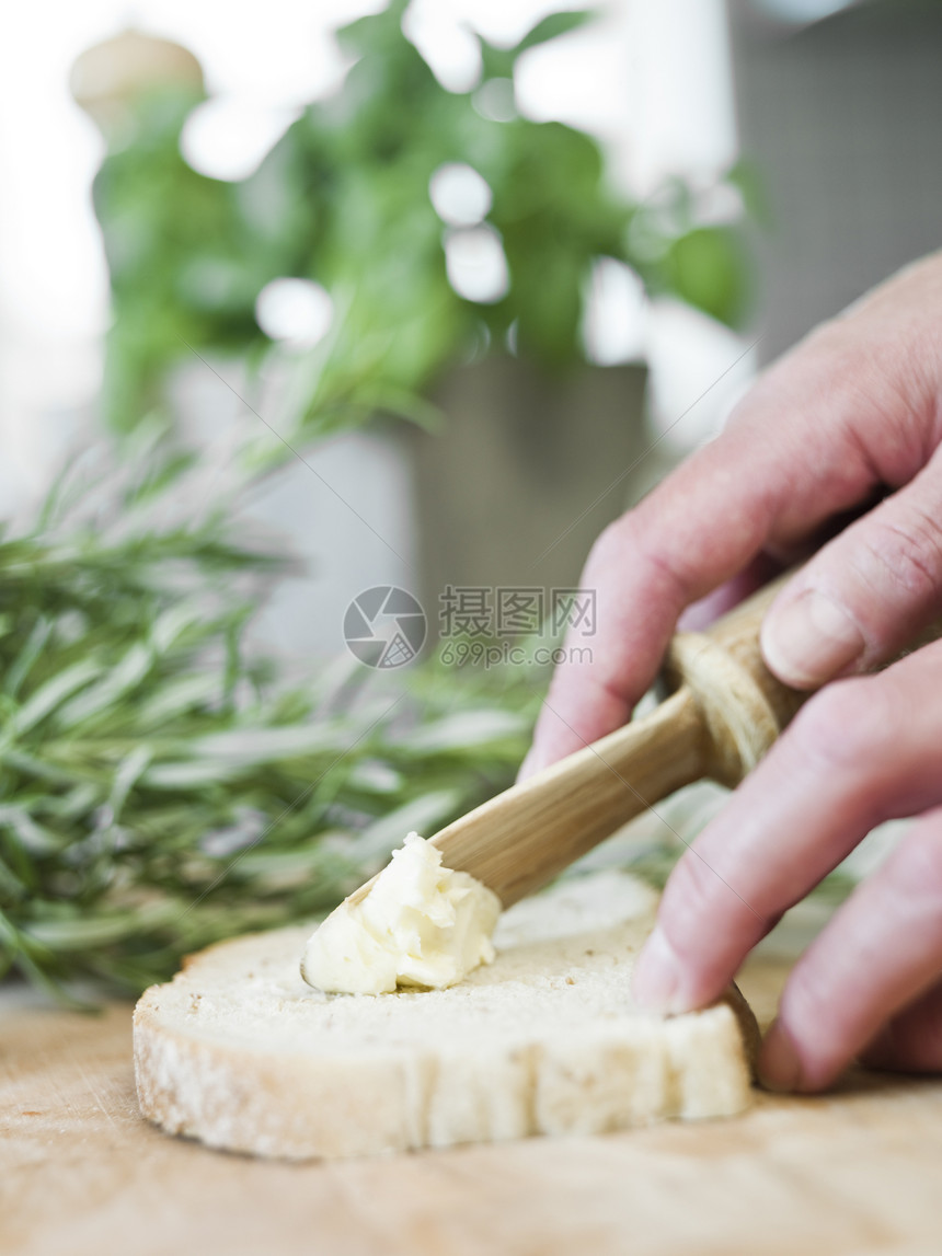 在面包上传播黄油桌子食物草药绿色小吃短焦西红柿早餐人类厨房图片
