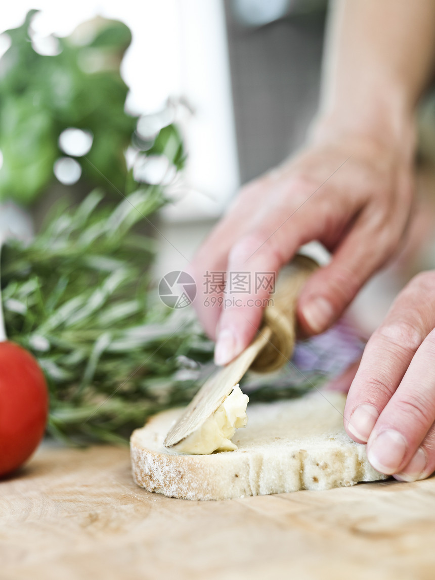 在面包上传播黄油小吃绿色宏观早餐短焦桌子人类西红柿厨房食物图片