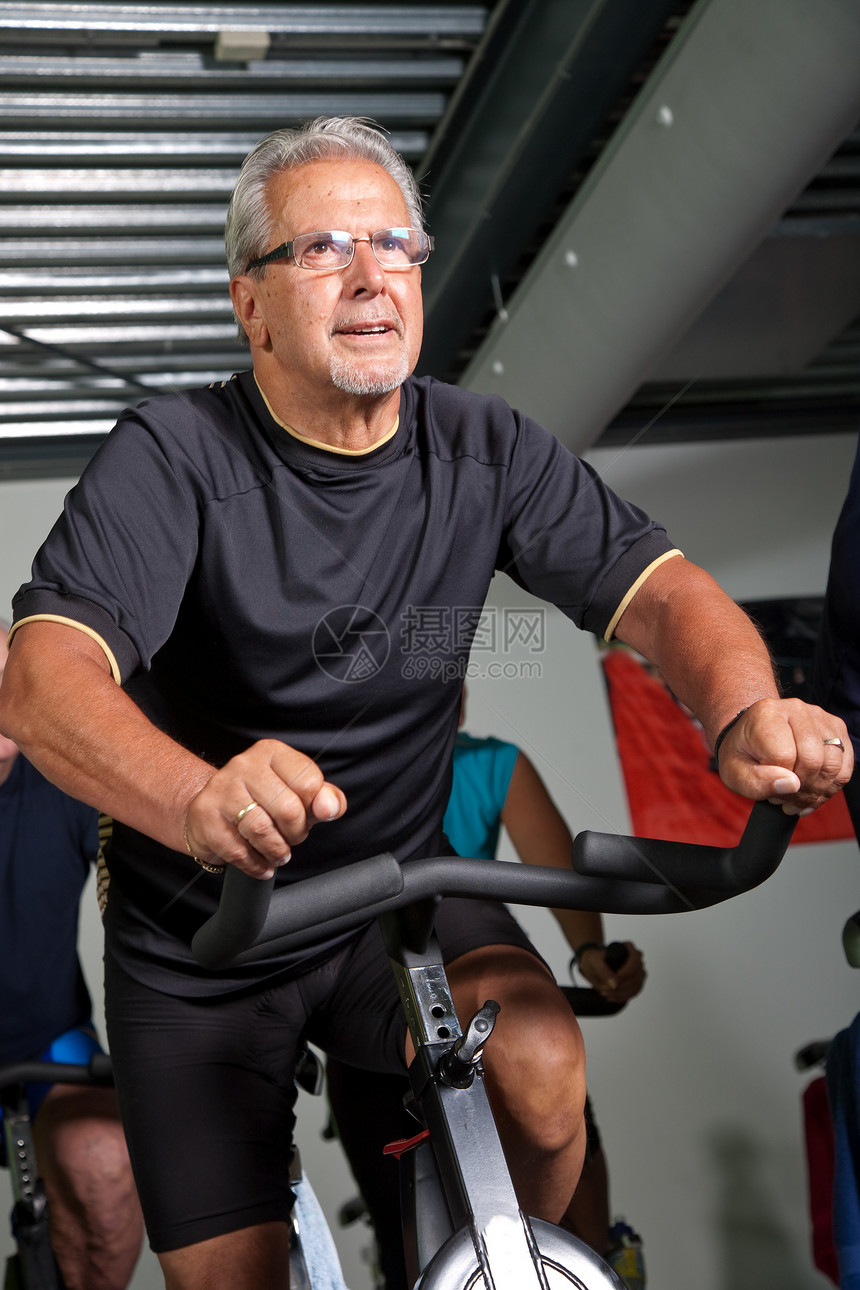 高级男子骑自行车老年人运动幸福成人眼镜纺纱活动健身房训练老年图片