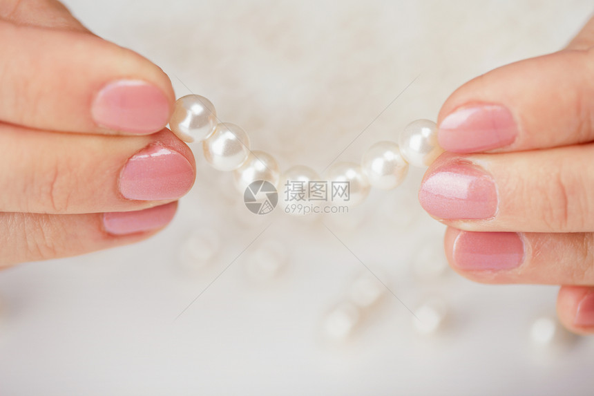 女性的手指紧紧结着珍珠图片