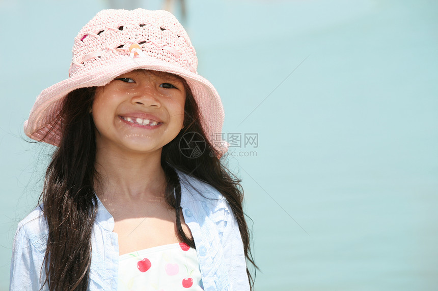 海滩上可爱的小女孩混血帽子享受粉色海滨女孩泳装牙齿乐趣混血儿图片