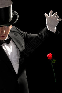 年轻魔术师表演红玫瑰黑色游戏娱乐手势玫瑰男人惊喜展示闲暇套装背景图片