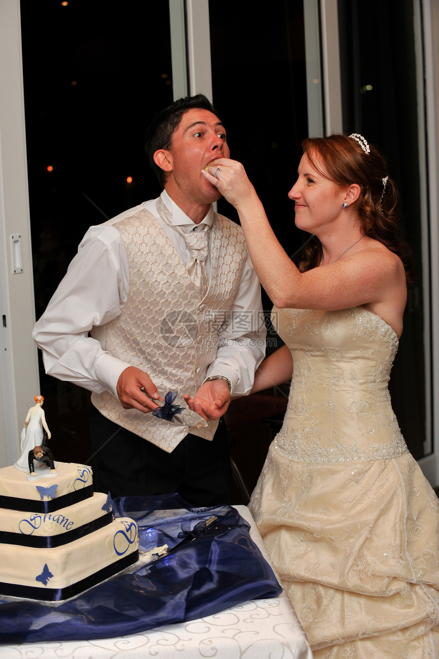 新娘用手和笑容喂新郎的婚礼蛋糕图片
