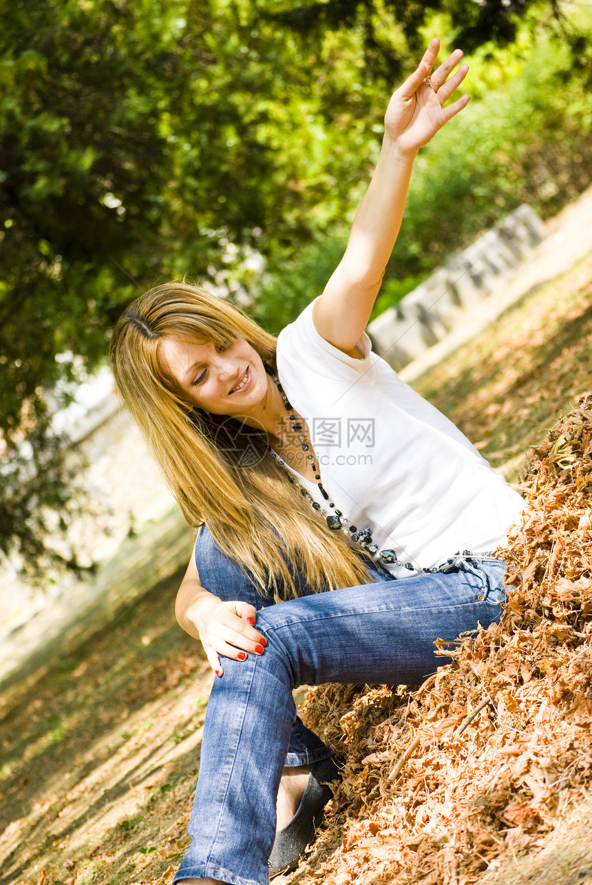 美丽的年轻女孩扔叶子女士公园衣服生活喜悦蓝色微笑女性金发眼睛图片