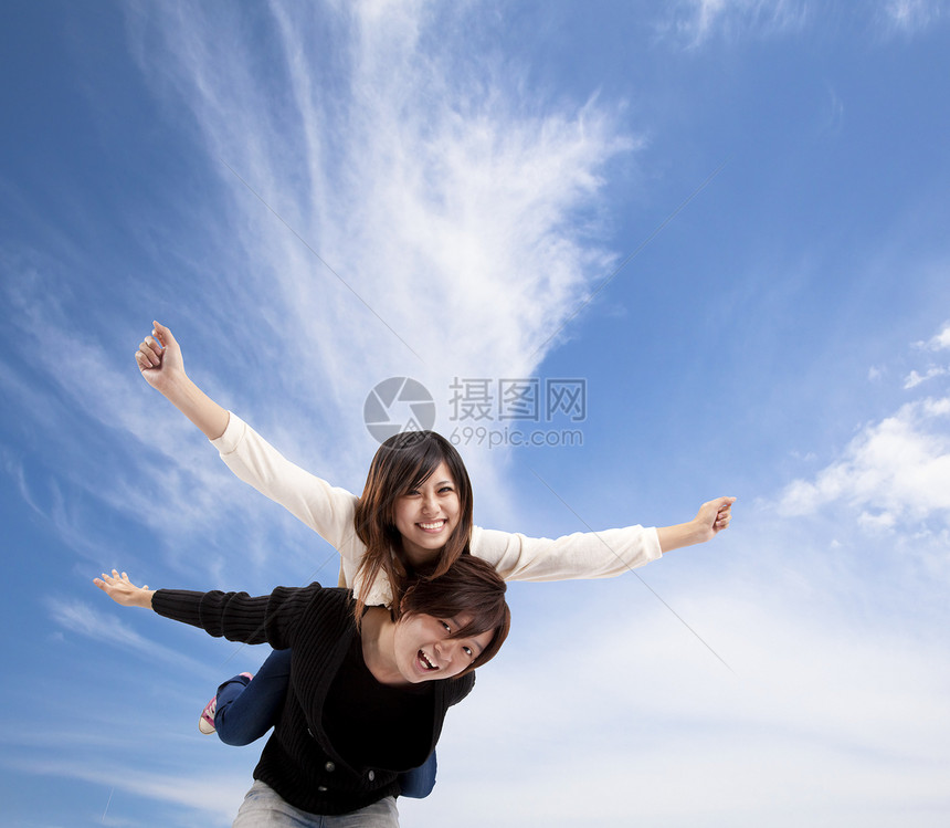 年轻亚洲情侣在蓝天空和云下微笑图片