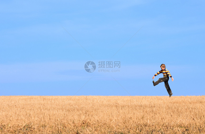 年轻男孩在田野上跳跃闲暇场地休闲草地蓝色孩子爬坡幸福天空青少年图片