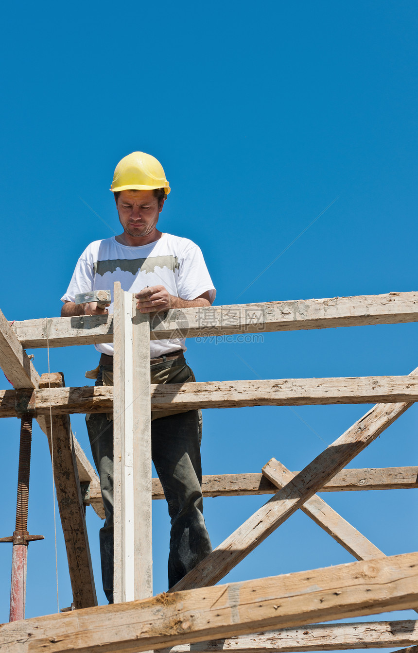 忙于形式工作准备工作的脚手架上的建筑工人图片