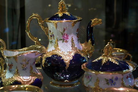 陈列盒装的古董瓷瓷茶咖啡金子飞碟咖啡店服务杯子盘子食物蛋糕蓝色茶壶背景图片