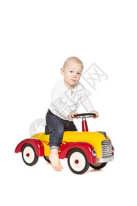 骑着车的男孩男孩骑着他的玩具车后代童年衬衫衣服工作室婴儿乐趣小男孩牛仔裤男士背景