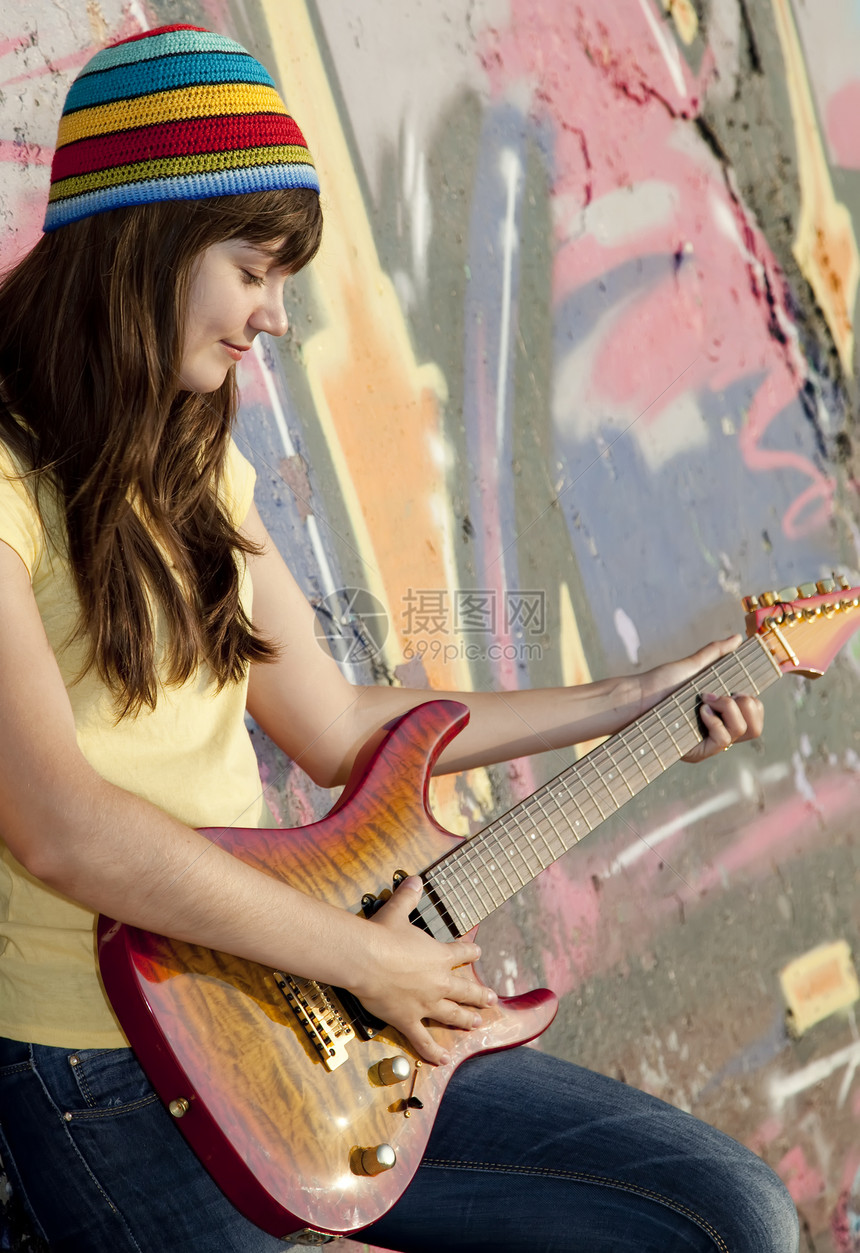 美丽的黑发美女 吉他和涂鸦墙在后院微笑青年女性城市幸福女孩白色帽子岩石街道图片