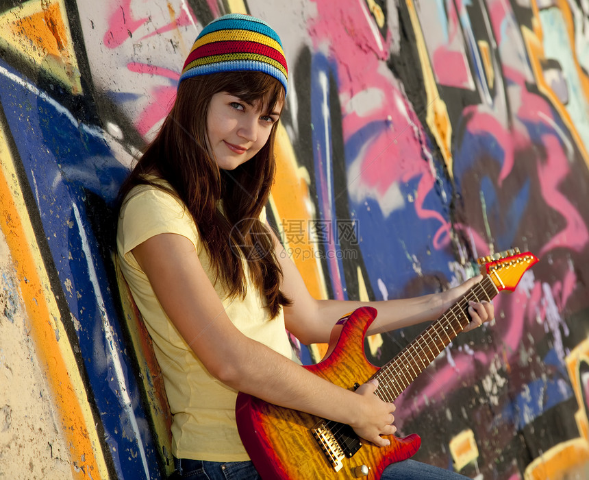 美丽的黑发美女 吉他和涂鸦墙在后院喜悦女孩青年幸福女士乐趣白色岩石城市青少年图片