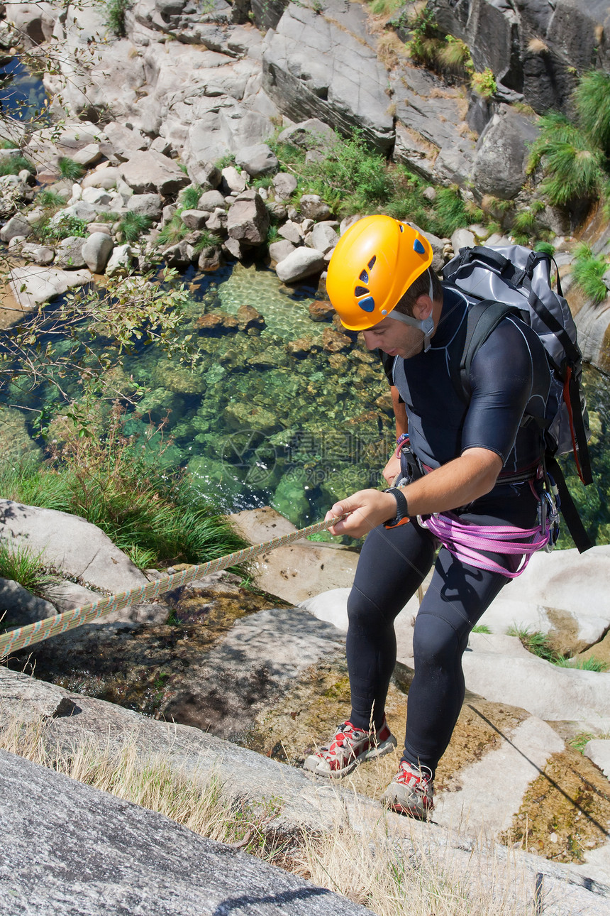 男人在瀑布下游行动峡谷系统假期地形边缘绳索男士极限冒险图片