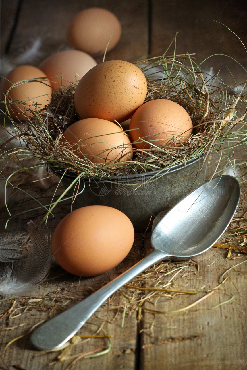 用勺子装在旧锡容器中的新鲜棕色鸡蛋图片