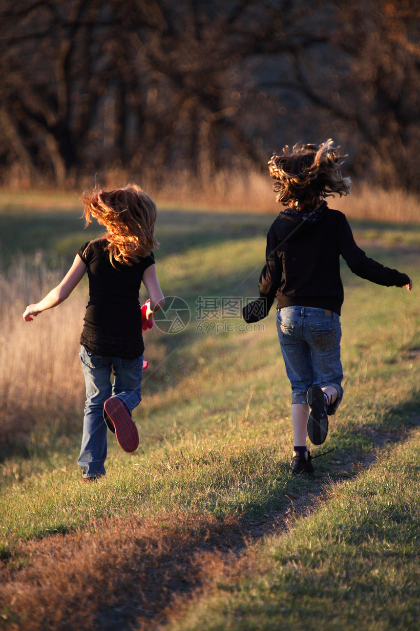 两名女孩在萨斯喀彻温的风景地带沿堤道跑动孩子们乡村活动避难所农村跑步女孩们图片