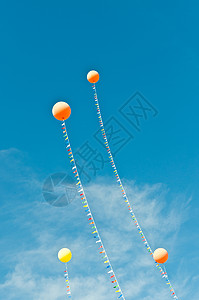 蓝色天空中流星流的气球黄色飘带橙子背景图片