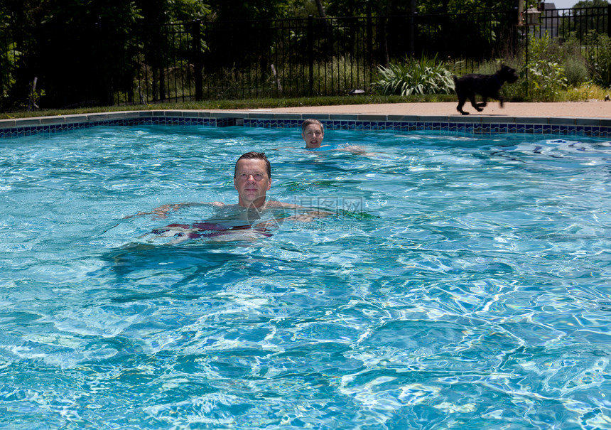 老年退休夫妇在游泳池游泳一代男性福利丈夫妻子闲暇后院蓝色成人游泳者图片
