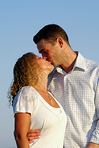 年轻夫妇在接吻拥抱恋人冒充假期喜悦男人男性女孩天空女士情人节高清图片素材