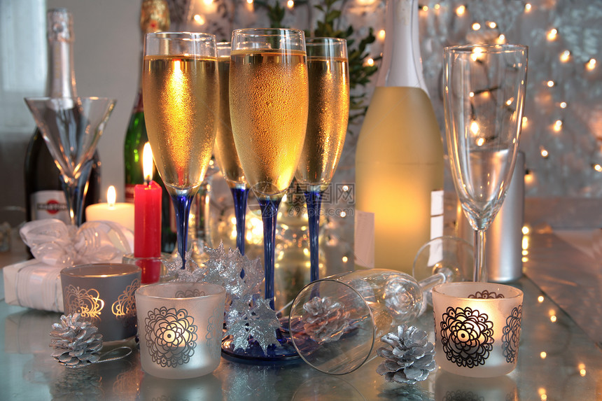 香槟在玻璃杯和蜡烛上的银色背景图片