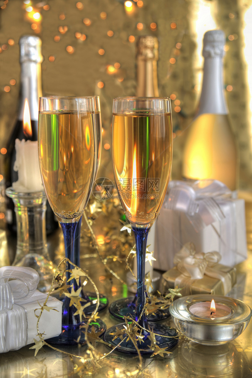 香槟装在眼镜上 蜡烛上 金色背景的胶囊上 闪亮的灯光图片