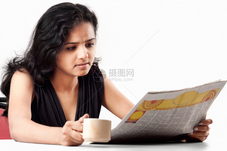 微笑印地安青少年阅读报纸加咖啡图片