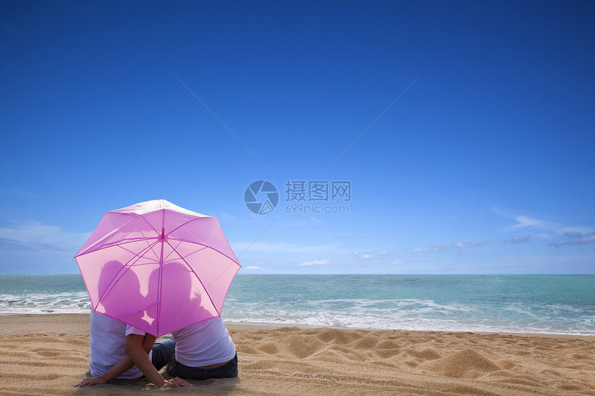 年轻情侣浪漫的亲吻 在海滩与雨伞在海滩上图片