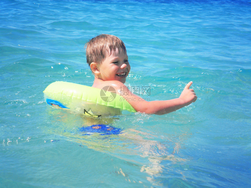 一个男孩在海中游泳海岸线支撑快乐闲暇晴天海洋童年蓝色海浪天空图片