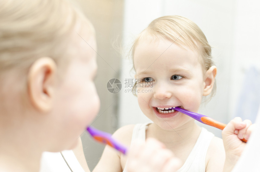 小女孩在刷牙时牙科微笑牙膏喜悦浴室洗澡蓝色塑料女孩眼睛图片