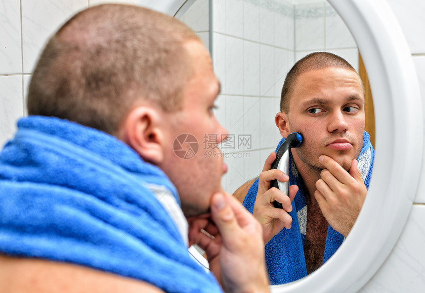男人在镜子前的浴室里刮毛巾护理剃刀反射蓝色修饰剃须刀刀刃剃须男性卫生图片