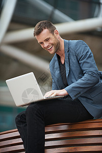 年轻人和笔记本电脑坐在一起互联网公园男性座位闲暇享受冲浪网络微笑幸福背景图片